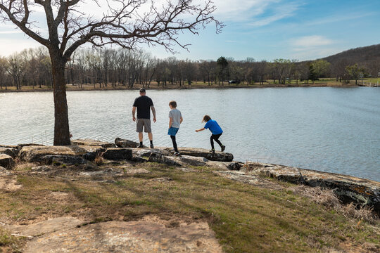 Father and two sons standing on a rocky lakeshore on a spring day