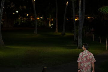 Obraz premium Man standing in Royal Hawaiian courtyard with palms at night