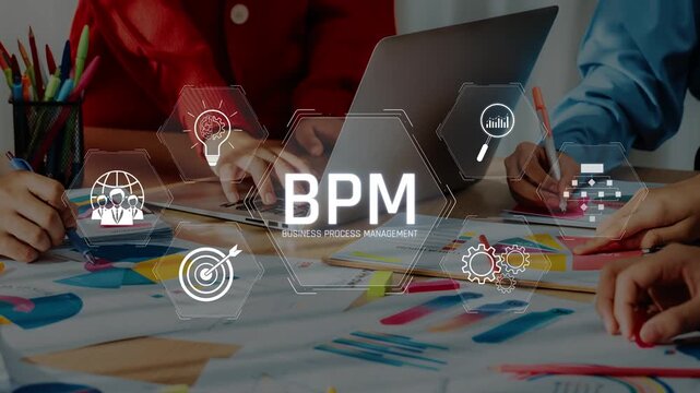 Team members collaborate on business process management with a laptop and colorful charts, focusing on innovation and strategy development in a dynamic office setting. Raster