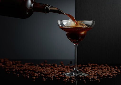 Coffee liquor is poured into a glass with ice.