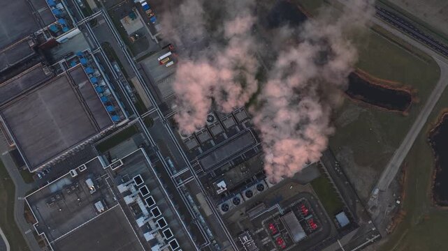 High angle aerial perspective of a modern ai data center releasing steam from its cooling systems into the air during sunset or sunrise