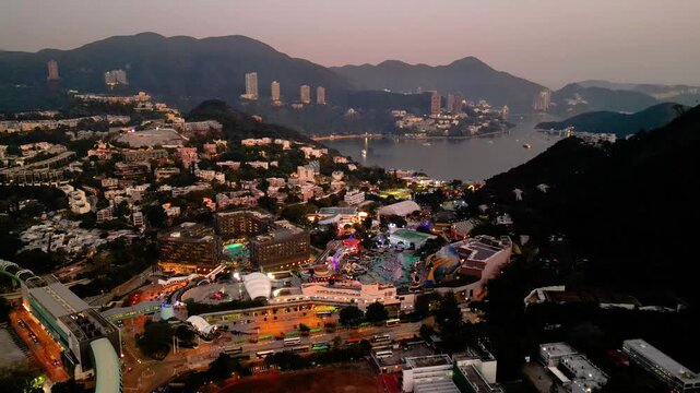 Cinematic drone shot capturing Hong Kong skyline at golden hour with mountains and ocean in the background. Showcases the unique blend of urban density and natural landscape, ideal for travel, tourism