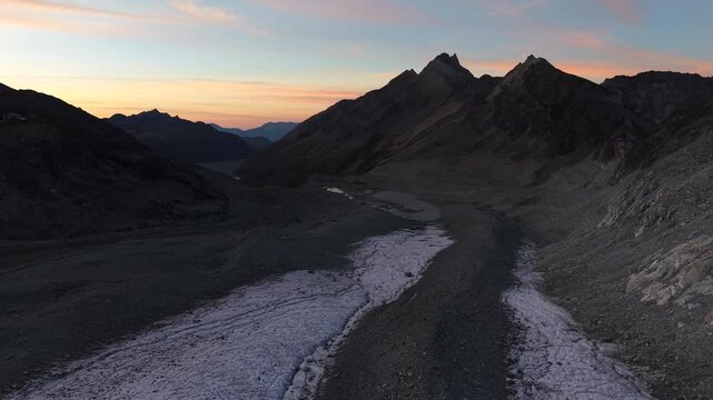 Aerial flyover across the glacial tongue of Glacier de Cheilon a sunset in the Swiss Alps with a view of the ice, moraines and glacial lake