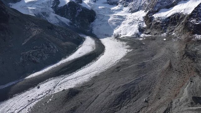 Aerial flyover around a mountain hut alongside Glacier de Cheilon as the morning sun shines over the mountain peaks of Swiss Alps in the Arolla region
