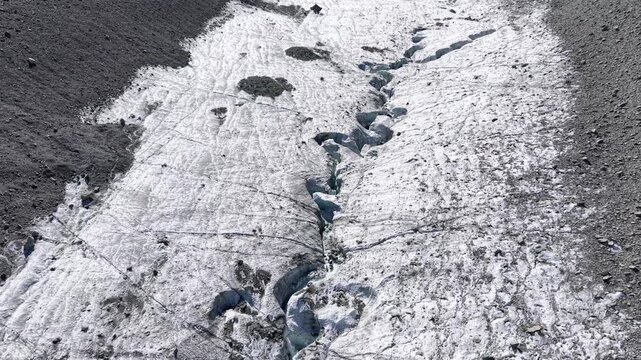 Aerial flyover over the ice of Glacier de Cheilon with a view of the crevasses and moraines