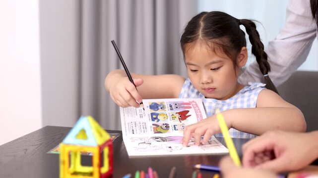 Young Girl Coloring With Parent at Home Table