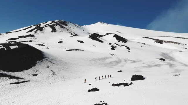 Aerial view of hikers trekking near Rifugio Sapienza on the snow-covered slopes of Mount Etna in Nicolosi, Sicilia, Italy.
