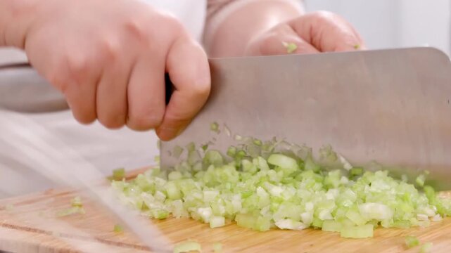 Unidentified hands woman baker chef chopping fresh chives or cutting green onions on kitchen board with knife to making tasty homemade dumplings stuffed with minced meat and vegetable for filling buns