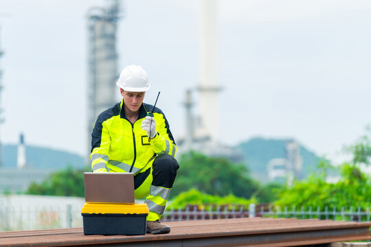 Railway engineer inspecting railroad track with laptop and radio communication device during railway maintenance operation, industrial transportation infrastructure worker checking rail system