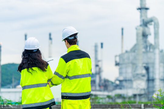 Petroleum refinery engineers and industrial worker working on laptop, inspection oil refinery plant at construction site with radio communication, technician teamwork maintaining energy power system