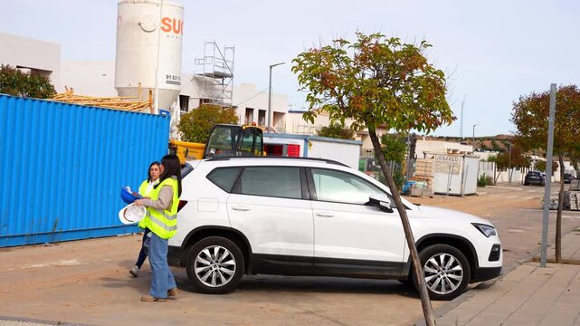 Two women professionals with safety gear meeting and walking at a building project location