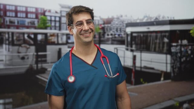 Man doctor in blue scrubs with red stethoscope smiling beside a canal boat on street; compassion care trust.