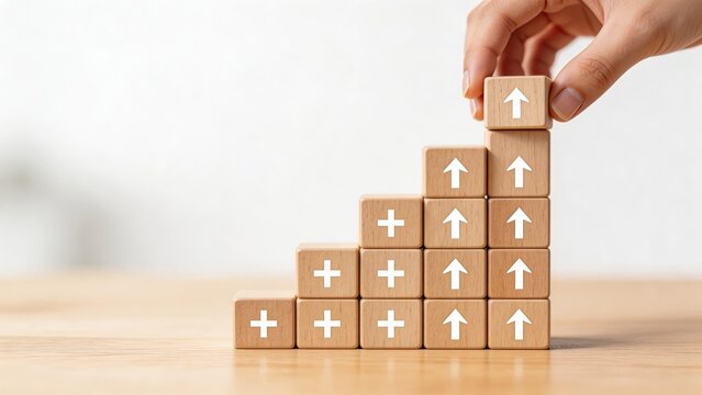 Hand placing wooden block with arrow symbol on top of growing staircase structure representing business growth financial success strategic planning career development progress