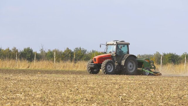 Agricultural tractor with seed drill plowing field during corn sowing, modern farming machinery cultivating soil and planting crops in rural farmland landscape