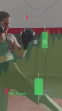Vertical video: Two women boxers training, pink-glove high kick starting financial charts animating