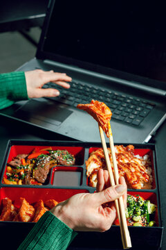 Girl eating gyoza with sauce from bento box. Flash. Business lunch