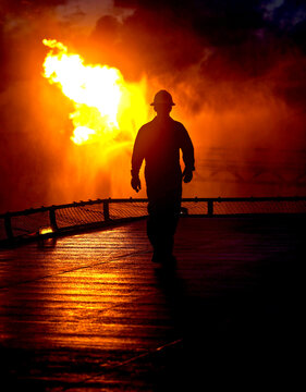 Offshore worker sihouetted by flare
