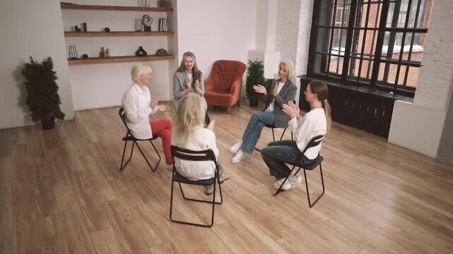 Women cheering each other in group therapy in psychological clinic, applauding. Diversity of women, different ages, appearance and professions, joining support group for psychological release