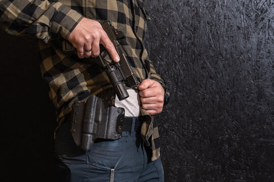 BALTIC STATES &ndash; MAY 6, 2026: Close-up of a shooter drawing a tactical Glock 19 Gen 5 pistol with a red dot sight and weapon light from a Kydex holster during training.