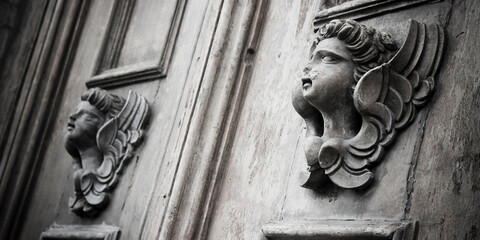Obraz premium Sculpture of an old wooden angel against a wooden door of a church - more than 100 years old
