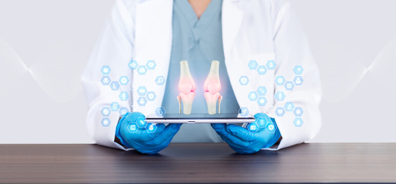 Doctor examining knee bones on a tablet, telemedicine platform. Mobile health app for joint effusion screening. The doctor examines bone anatomy on his tablet.