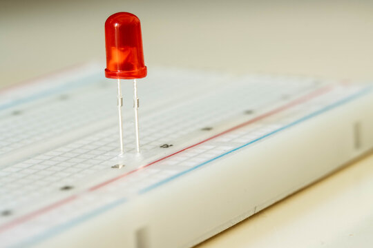 Red LED on breadboard close up, electronic component concept