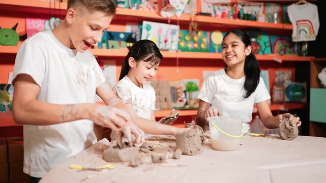 Caucasian high school girl modeling cup of clay while looking smart boy in art class at workshop. Multicultural student playing or making cup of clay art in creative activity. Education. Edification