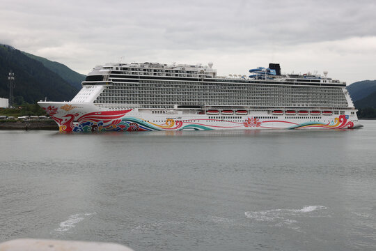 Juneau, Alaska - July 25, 2025: The Norwegian Joy cruise ship docked in the Gastineau Channel surrounded by lush green mountains on a cloudy summer day