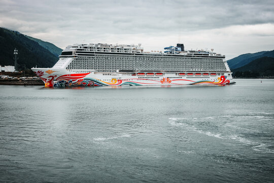 Juneau, Alaska - July 25, 2025: The Norwegian Joy cruise ship docked in the Gastineau Channel surrounded by lush green mountains on a cloudy summer day