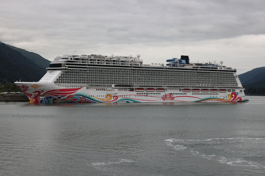 Juneau, Alaska - July 25, 2025: The Norwegian Joy cruise ship docked in the Gastineau Channel surrounded by lush green mountains on a cloudy summer day