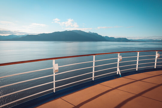 view of majestic alaskan mountains and calm ocean from a luxury cruise ship deck at sunrise