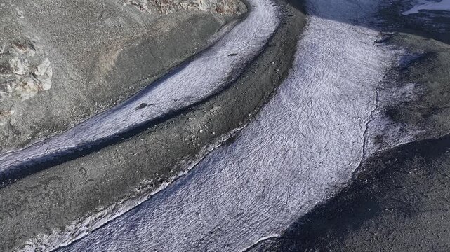 Aerial flyover next to the Glacier de Cheilon on a sunny summer day in the Swiss Alps with a pan up view towards the mountain peaks of Arolla such as Mont Blanc de Cheilon