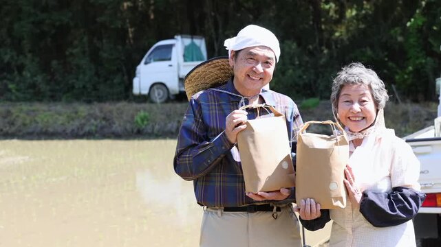 お米を手に笑顔を見せるシニア農家夫婦