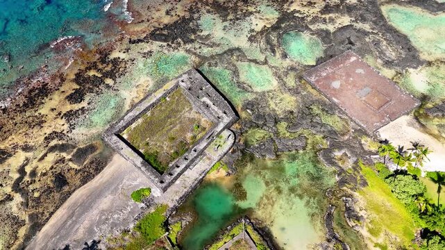 Aerial view of the ancient stone heiau ruins at Kahaluu Beach Park with turquoise coastal waters and volcanic rock formations in Kailua-Kona, Hawaii, United States.