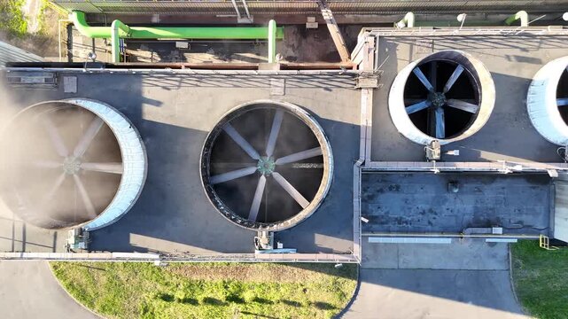 Aerial view of industrial cooling system with large fans and green ventilation units on a factory roof, showcasing continuous airflow and operational efficiency in a manufacturing environment