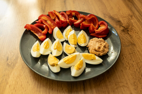 Top view of healthy breakfast. Hard boiled eggs on a plate, salmon pate and red pepper. Wood background