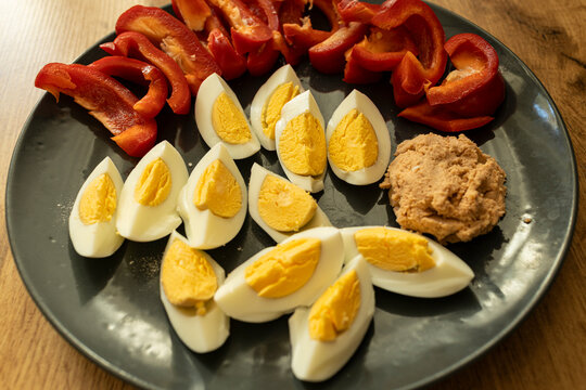 Top view of healthy breakfast. Hard boiled eggs on a plate, salmon pate and red pepper. Wood background