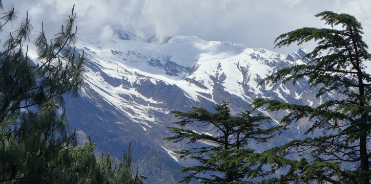 Beautiful landscapes of Harsil Valley with rivers mountains and deodar forests. Scenic Himalayan views of Harsil Valley featuring rivers, waterfalls, snow-covered mountains, and dense deodar forests.
