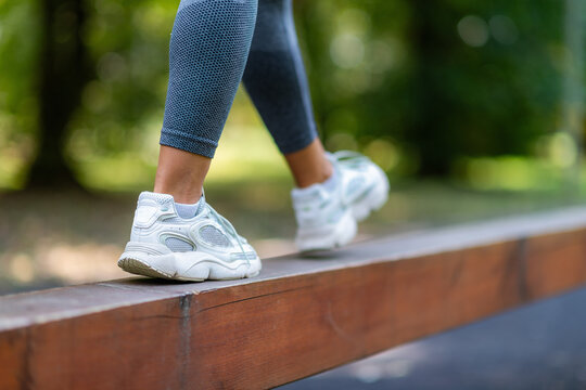 Detailed view of sport shoes on narrow beam during outdoor balance training and functional fitness workout.