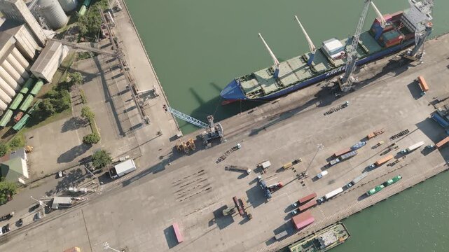 Poti, Georgia - 22nd august, 2025: Aerial top down view Cargo ship docked busy black sea seaport quay with cranes, containers, trucks, logistics operations, imports, exports, international trade hub
