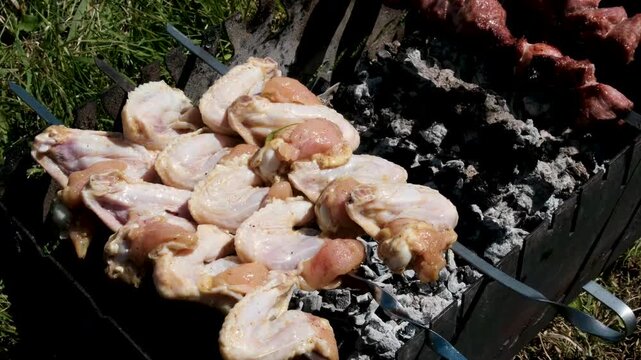process of preparing chicken wings for grilling. In one, wings are threaded onto skewers, and in the other, they are cooked over a barbecue grill, capturing a complete outdoor cooking sequence. 