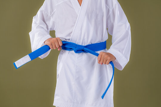 Boy adjusting his karate belt in standing position. Shows readiness, disciplined posture, and foundational technique.