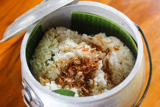 Nasi Liwet, a traditional Indonesian flavored rice dish, served in a rustic metal pot. The rice is topped with crispy fried anchovies (ikan teri) and fried shallots (bawang goreng).