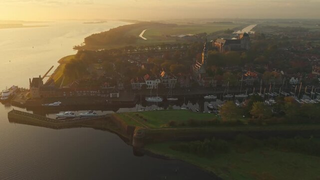 Aerial view of the historic town of Veere with its church tower and harbor during a golden sunrise over the water in Veere, Zeeland, Netherlands.