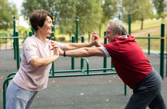 elderly man and woman do gymnastics on an outdoor sports ground