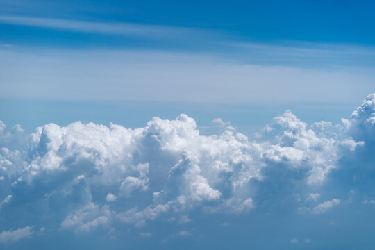 Beautiful white cumulus clouds against a bright blue sky view from above.