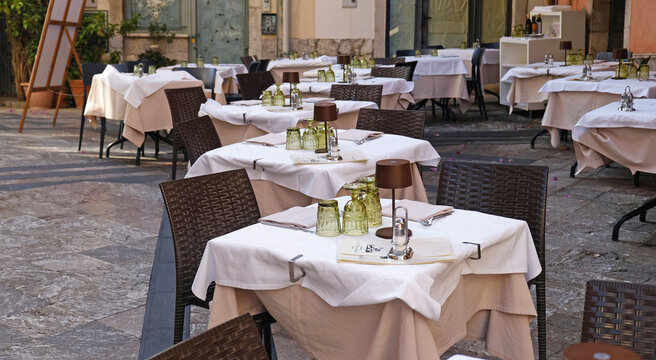 Elegant outdoor restaurant terrace with fully set tables. Refined dining atmosphere for hospitality, travel, and leisure marketing.