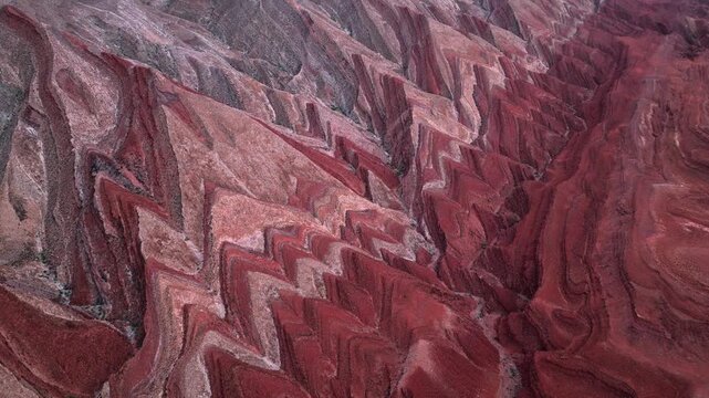 Aerial view of the unique red rock formations and jagged geological ridges under soft light in the desert landscape of Moab, Utah, United States.