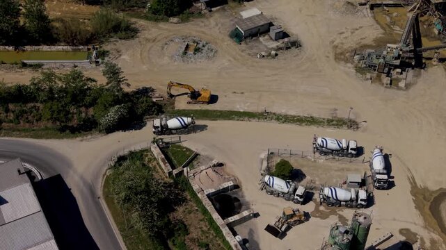 Mixer trucks line up in queue to load fresh concrete in an active industrial production site.
