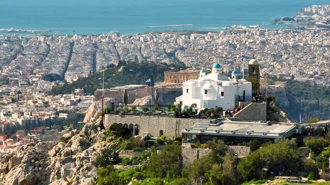 Drone zoom on Lycabettus Hill chapel with Athens city stretching behind